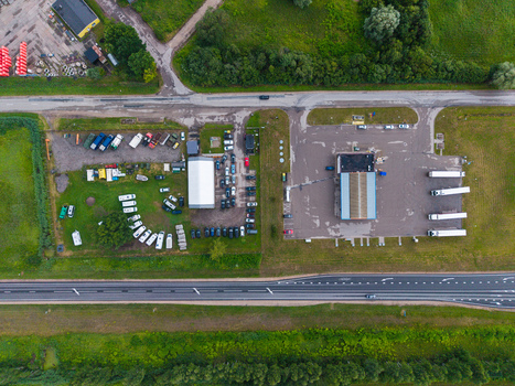 Aerial view of a gas station and a used car dealer with parked vehicles and trucks situated along a highway in Cenu pagasts Jelgavas novads Latvia.
