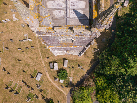 Aerial view of St Ildierna s Church tower surrounded by an ancient graveyard with weathered headstones and dry grass in Lansallos England United Kingdom. Aerial view of St Ildierna s Church tower surrounded by an ancient graveyard with weathered headstones and dry grass in Lansallos England United Kingdom.