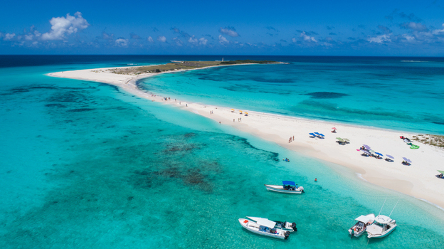 Aerial view of Los Roques archipelago featuring white sand beaches turquoise Caribbean waters and small boats anchored near the shore in Los Roques Dependencias Federales Venezuela. Aerial view of Los Roques archipelago featuring white sand beaches turquoise Caribbean waters and small boats anchored near the shore in Los Roques Dependencias Federales Venezuela.