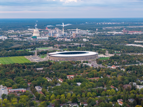Aerial view of Olympiastadion Berlin surrounded by lush green trees and urban infrastructure in Berlin Berlin Germany.