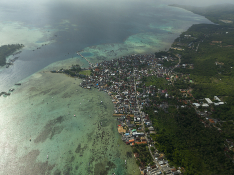 Aerial view of the town sprawling along the coast where the azure sea meets the vibrant green forests Karimunjawa Central Java Indonesia. Aerial view of the town sprawling along the coast where the azure sea meets the vibrant green forests Karimunjawa Central Java Indonesia.