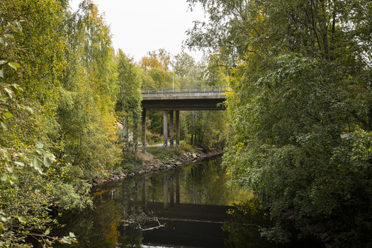 View of a concrete bridge spanning a calm canal surrounded by lush autumn trees with yellow and green foliage in Jyvaskyla Central Finland Finland.