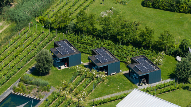 Aerial view of Ecodorp Bolderburen featuring modern houses with solar panels lush green gardens vineyards and a swimming pool in Almere Flevoland Netherlands. Aerial view of Ecodorp Bolderburen featuring modern houses with solar panels lush green gardens vineyards and a swimming pool in Almere Flevoland Netherlands.