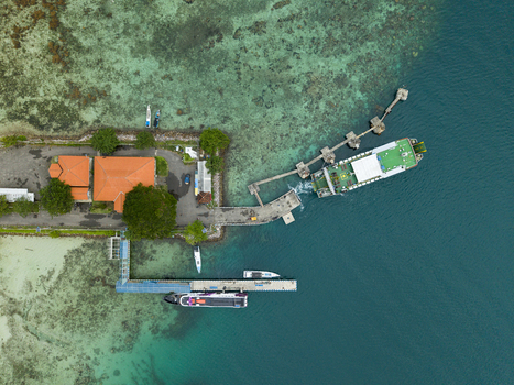 Aerial view of ferries docked at the pier with buildings and lush trees along the coast contrasted by the turquoise sea Karimunjawa Jawa Tengah Indonesia. Aerial view of ferries docked at the pier with buildings and lush trees along the coast contrasted by the turquoise sea Karimunjawa Jawa Tengah Indonesia.