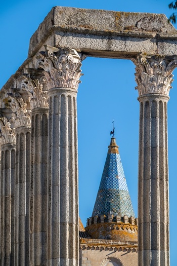 Evora Distrito de Evora Portugal 09 September 2026 View of the Roman Temple of Evora with ancient granite columns framing the tiled cathedral spire under a clear blue sky. Evora Distrito de Evora Portugal 09 September 2026 View of the Roman Temple of Evora with ancient granite columns framing the tiled cathedral spire under a clear blue sky.