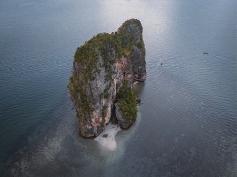 Aerial view of a majestic limestone island rising from the turquoise sea its cliffs crowned with lush greenery Krabi Thailand. Aerial view of a majestic limestone island rising from the turquoise sea its cliffs crowned with lush greenery Krabi Thailand.