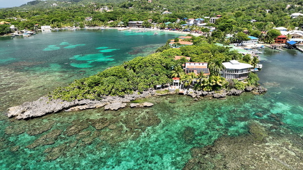 Aerial view of the lush coastline and vibrant turquoise coral reefs at West End Bay Islands Department Honduras.