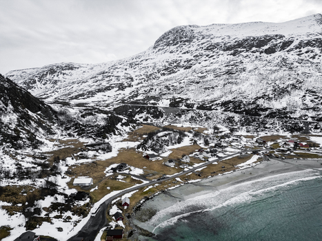 Aerial view of Grotfjord with snow covered mountains scattered houses along the coast and a sandy beach in Tromvik Troms Norway. Aerial view of Grotfjord with snow covered mountains scattered houses along the coast and a sandy beach in Tromvik Troms Norway.
