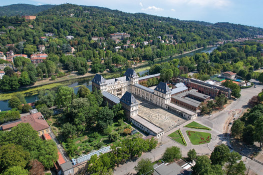 Aerial view of Castello del Valentino with its grand courtyard and historic architecture along the Po River and lush green hills in the background in Torino Piemonte Italy. Aerial view of Castello del Valentino with its grand courtyard and historic architecture along the Po River and lush green hills in the background in Torino Piemonte Italy.
