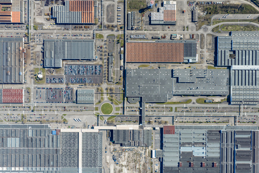Aerial view of industrial rooftops and organised parking spaces create a geometric puzzle of textures and tones contrasting with small patches of green Sausheim Grand Est France.