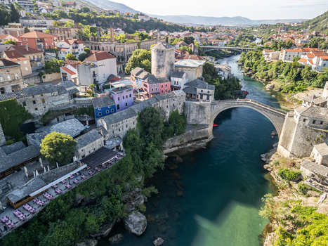 Mostar Bosnia and Herzegovina 28 May 2025 Aerial view of Old Bridge Mostar spanning the emerald Neretva River surrounded by historic stone buildings rooftops and lush greenery under a clear sky. Mostar Bosnia and Herzegovina 28 May 2025 Aerial view of Old Bridge Mostar spanning the emerald Neretva River surrounded by historic stone buildings rooftops and lush greenery under a clear sky.