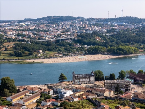 Aerial view of Praia Fluvial do Areinho along the Douro River with urban buildings lush greenery and a bridge in the background in Vila Nova de Gaia Porto Portugal.