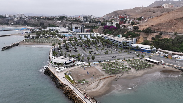 Aerial view of the BCP building complex with its parking lot palm trees and beach umbrellas along the coastline in Chorrillos Provincia de Lima Peru.
