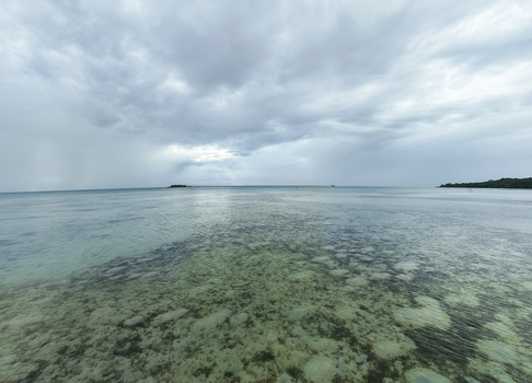 Aerial view of the tranquil sea where the water s gentle turquoise hue meets the horizon under a sky heavy with clouds Karimunjawa Central Java Indonesia.