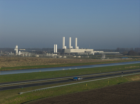 Aerial view of the nitrogen plant with tall white chimneys industrial structures a canal and a highway under a clear blue sky in Zuidbroek Groningen Netherlands. Aerial view of the nitrogen plant with tall white chimneys industrial structures a canal and a highway under a clear blue sky in Zuidbroek Groningen Netherlands.