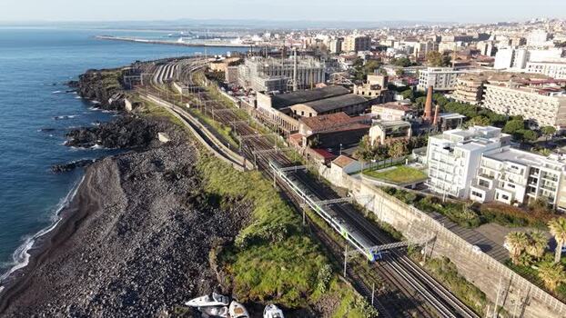 Aerial view of a train on tracks along the coast in Catania Italy. Aerial view of a train on tracks along the coast in Catania Italy.
