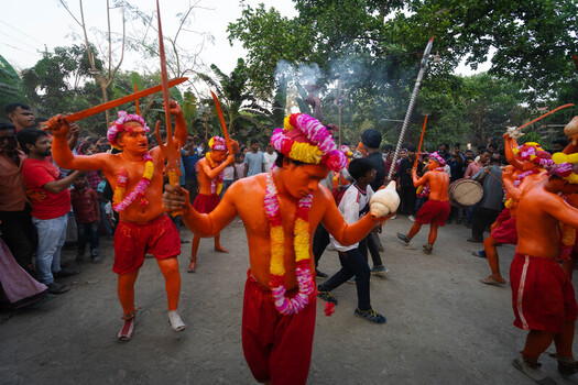 Munshiganj Bangladesh 13 April 2025 View of performers adorned in vibrant orange and red wielding wooden swords amidst a festive gathering under a smoky haze. Munshiganj Bangladesh 13 April 2025 View of performers adorned in vibrant orange and red wielding wooden swords amidst a festive gathering under a smoky haze.
