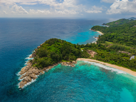 Aerial view of turquoise waters meet lush green forests creating a vibrant contrast against the rocky coastline Police bay Mahe Island Seychelles. Aerial view of turquoise waters meet lush green forests creating a vibrant contrast against the rocky coastline Police bay Mahe Island Seychelles.