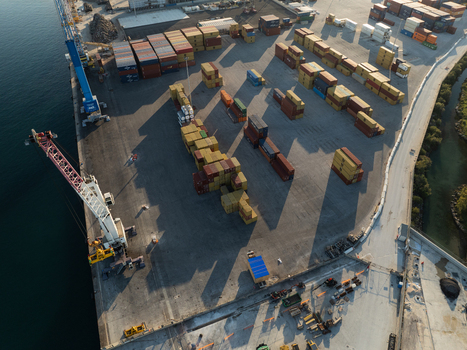 Aerial view of a shipping port with stacked cargo containers industrial cranes and a concrete pier under soft daylight in Augusta Sicily Italy. Aerial view of a shipping port with stacked cargo containers industrial cranes and a concrete pier under soft daylight in Augusta Sicily Italy.