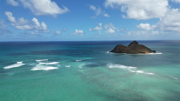 Aerial view of the Mokulua Islands twin volcanic islets amidst turquoise waters and foamy white waves under a bright sky Kailua Hawaii United States. Aerial view of the Mokulua Islands twin volcanic islets amidst turquoise waters and foamy white waves under a bright sky Kailua Hawaii United States.