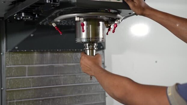 View of a worker installing a tool in a CNC machine Bangladesh.