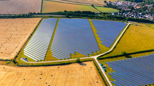 Aerial view of a large solar farm with rows of photovoltaic panels in rural fields surrounded by harvested agricultural land in Dorset England United Kingdom. Aerial view of a large solar farm with rows of photovoltaic panels in rural fields surrounded by harvested agricultural land in Dorset England United Kingdom.