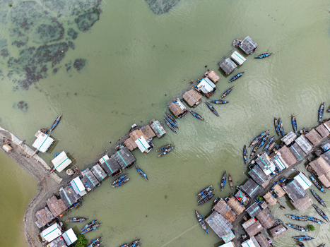 Aerial view of Kalabagi fishing village with traditional huts and numerous small boats moored in the murky green water Khulna District Khulna Division Bangladesh.