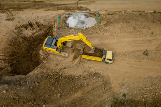 Aerial view of a yellow excavator loading soil into a dump truck at a construction site in Salatiga Central Java Indonesia.