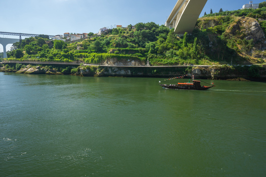 Aerial view of a traditional boat gliding on the serene green waters under the towering Arrábida Bridge Porto Porto District Portugal. Aerial view of a traditional boat gliding on the serene green waters under the towering Arrábida Bridge Porto Porto District Portugal.