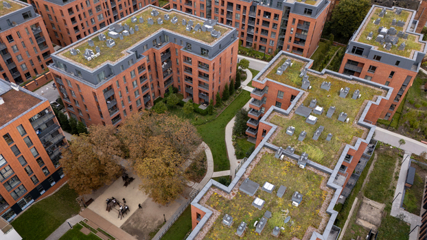 Aerial view of a modern residential complex featuring brick buildings with green roofs and a central courtyard with walkways in Gdansk Poland. Aerial view of a modern residential complex featuring brick buildings with green roofs and a central courtyard with walkways in Gdansk Poland.