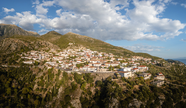 Aerial view of the historic village of Dhermi nestled on a lush green hillside with white stone houses and winding roads in Dhermi Vlore County Albania.