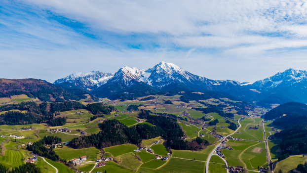 Aerial view of verdant fields contrasting with the snow capped peaks under a bright sky Windischgarsten Upper Austria Austria. Aerial view of verdant fields contrasting with the snow capped peaks under a bright sky Windischgarsten Upper Austria Austria.