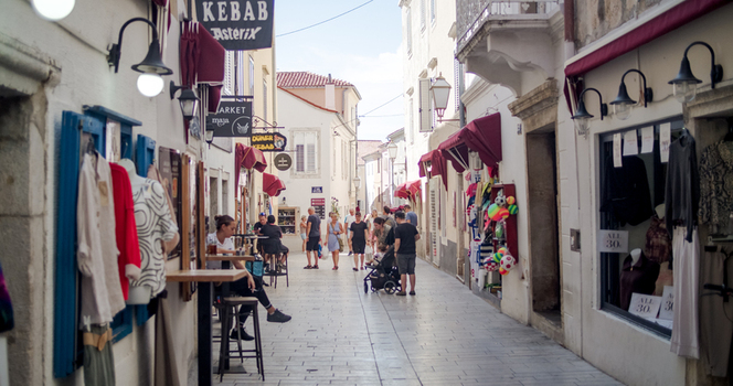 Krk Primorje Gorski Kotar Croatia 19 September 2026 View of a narrow street in the historic old town featuring stone buildings shop displays and people walking along the cobblestone path.