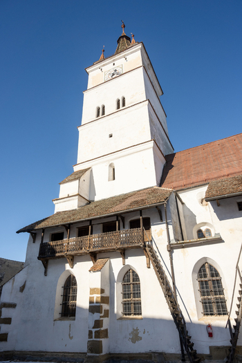 View of the white tower and wooden balcony of the historic Prejmer Fortified Church under a clear blue sky in Prejmer Brasov Romania. View of the white tower and wooden balcony of the historic Prejmer Fortified Church under a clear blue sky in Prejmer Brasov Romania.