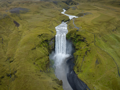 Aerial view of Skógafoss waterfall cascading powerfully through the verdant Icelandic landscape contrasting with the dark rocky terrain below Skógafoss Rangárþing eystra Iceland. Aerial view of Skógafoss waterfall cascading powerfully through the verdant Icelandic landscape contrasting with the dark rocky terrain below Skógafoss Rangárþing eystra Iceland.