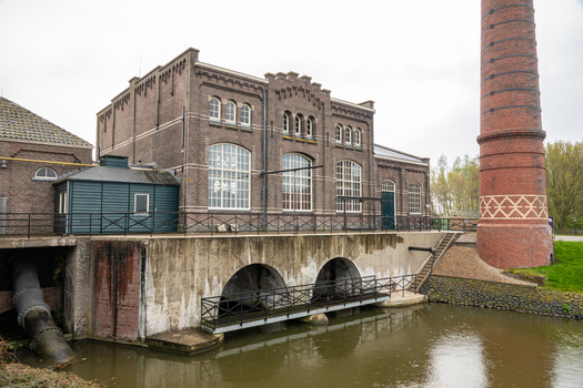 View of the Dutch Steam Engine Museum with its historic brick facade and tall chimney by the water in Medemblik Noord Holland Netherlands. View of the Dutch Steam Engine Museum with its historic brick facade and tall chimney by the water in Medemblik Noord Holland Netherlands.
