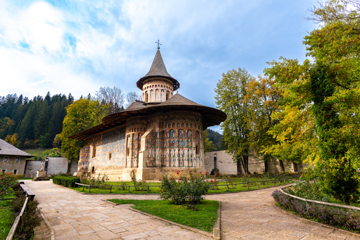 View of the historic Voronet Monastery with its famous painted exterior walls surrounded by lush autumn trees and stone pathways in Voronet Judetul Suceava Romania. View of the historic Voronet Monastery with its famous painted exterior walls surrounded by lush autumn trees and stone pathways in Voronet Judetul Suceava Romania.