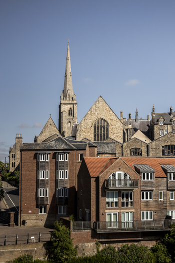 View of the historic Durham Cathedral rising above traditional brick buildings and red tiled rooftops in the city center of Durham England United Kingdom. View of the historic Durham Cathedral rising above traditional brick buildings and red tiled rooftops in the city center of Durham England United Kingdom.