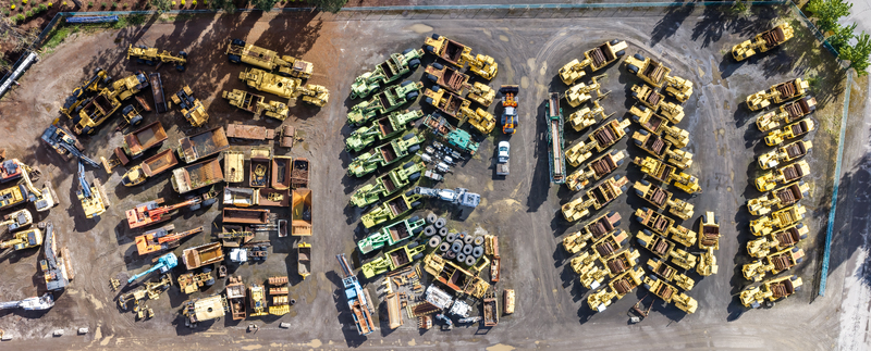 Aerial view of a large industrial yard filled with various heavy construction machinery including excavators loaders and dump trucks arranged in rows in Woodburn Oregon United States. Aerial view of a large industrial yard filled with various heavy construction machinery including excavators loaders and dump trucks arranged in rows in Woodburn Oregon United States.