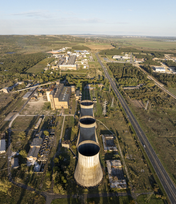 Aerial view of the abandoned Inota Power Plant cooling towers surrounded by industrial buildings trees and a road in Varpalota Hungary. Aerial view of the abandoned Inota Power Plant cooling towers surrounded by industrial buildings trees and a road in Varpalota Hungary.