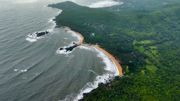 Aerial view of Om Beach with its distinctive shape rocky headlands crashing waves and lush tropical forest in Gokarna Karnataka India. Aerial view of Om Beach with its distinctive shape rocky headlands crashing waves and lush tropical forest in Gokarna Karnataka India.