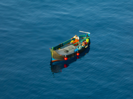 Aerial view of a small boat adrift on the tranquil sapphire expanse of the sea its vibrant red buoys standing out against the deep blue waters Ghajnsielem gozo Malta. Aerial view of a small boat adrift on the tranquil sapphire expanse of the sea its vibrant red buoys standing out against the deep blue waters Ghajnsielem gozo Malta.