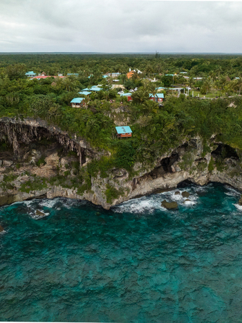 Aerial view of turquoise waters meet dramatic cliffs where buildings perch amidst lush greenery Joking Lifou New Caledonia. Aerial view of turquoise waters meet dramatic cliffs where buildings perch amidst lush greenery Joking Lifou New Caledonia.