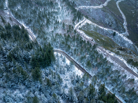 Aerial view of a winding mountain road passing through the snow covered pine forests of Serra da Estrela Unhais da Serra Castelo Branco District Portugal. Aerial view of a winding mountain road passing through the snow covered pine forests of Serra da Estrela Unhais da Serra Castelo Branco District Portugal.