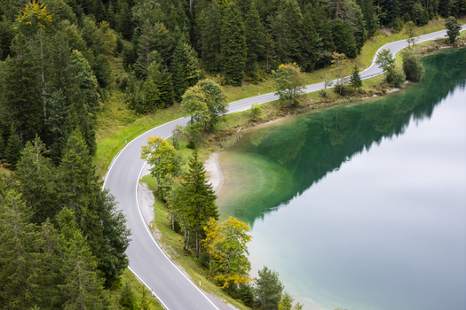 Aerial view of the winding road embracing the turquoise Plansee lake contrasting with the verdant forest creating a breathtaking scene Plansee Tyrol Austria. Aerial view of the winding road embracing the turquoise Plansee lake contrasting with the verdant forest creating a breathtaking scene Plansee Tyrol Austria.