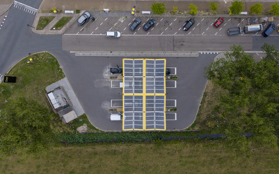 Aerial view of the Fastned charging station with solar panel roof parked electric vehicles and surrounding greenery in Beesd Gelderland Netherlands. Aerial view of the Fastned charging station with solar panel roof parked electric vehicles and surrounding greenery in Beesd Gelderland Netherlands.