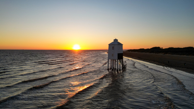 Aerial view of the Burnham on Sea Low Lighthouse standing on stilts in the shallow water at sunset with gentle waves and a golden sky in Burnham on Sea England United Kingdom. Aerial view of the Burnham on Sea Low Lighthouse standing on stilts in the shallow water at sunset with gentle waves and a golden sky in Burnham on Sea England United Kingdom.
