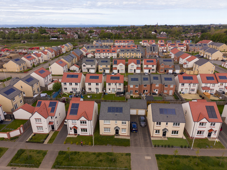 Aerial view of modern residential houses with solar panels on rooftops and green gardens in a suburban neighborhood Edinburgh Scotland United Kingdom.