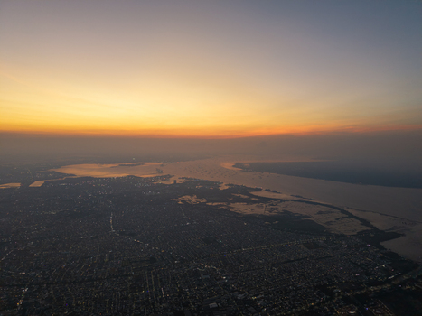 Aerial view of the city of Surabaya at sunset with the coastline and urban sprawl visible under a golden sky Surabaya East Java Indonesia.