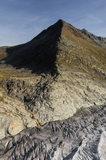 Aerial view of Aletsch Glacier with its rugged ice formations and surrounding rocky mountain slopes under a clear blue sky in Fieschertal Valais Switzerland. Aerial view of Aletsch Glacier with its rugged ice formations and surrounding rocky mountain slopes under a clear blue sky in Fieschertal Valais Switzerland.